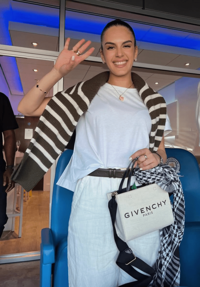 Woman waving while holding a Givenchy bag.