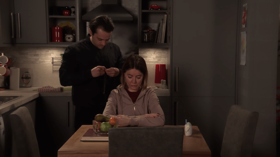 A man helps a woman in a kitchen.