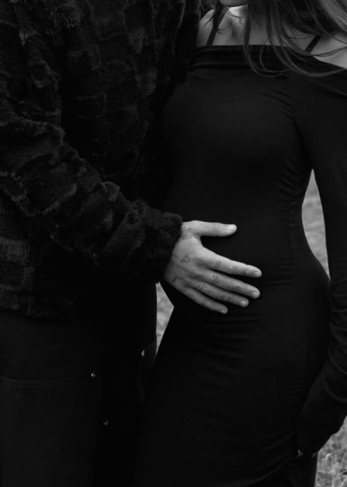 Black and white photo of a pregnant woman being embraced by a man.