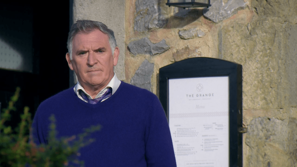 Man in a blue sweater standing outside The Grange restaurant.