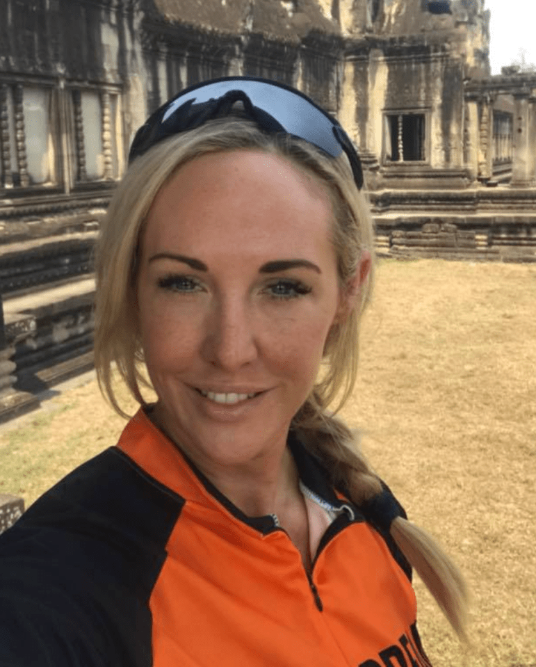 Woman in cycling jersey at ancient ruins.