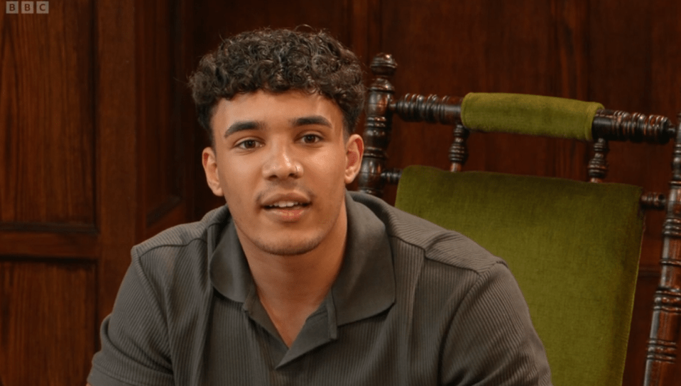 A young man sits in a chair and speaks.