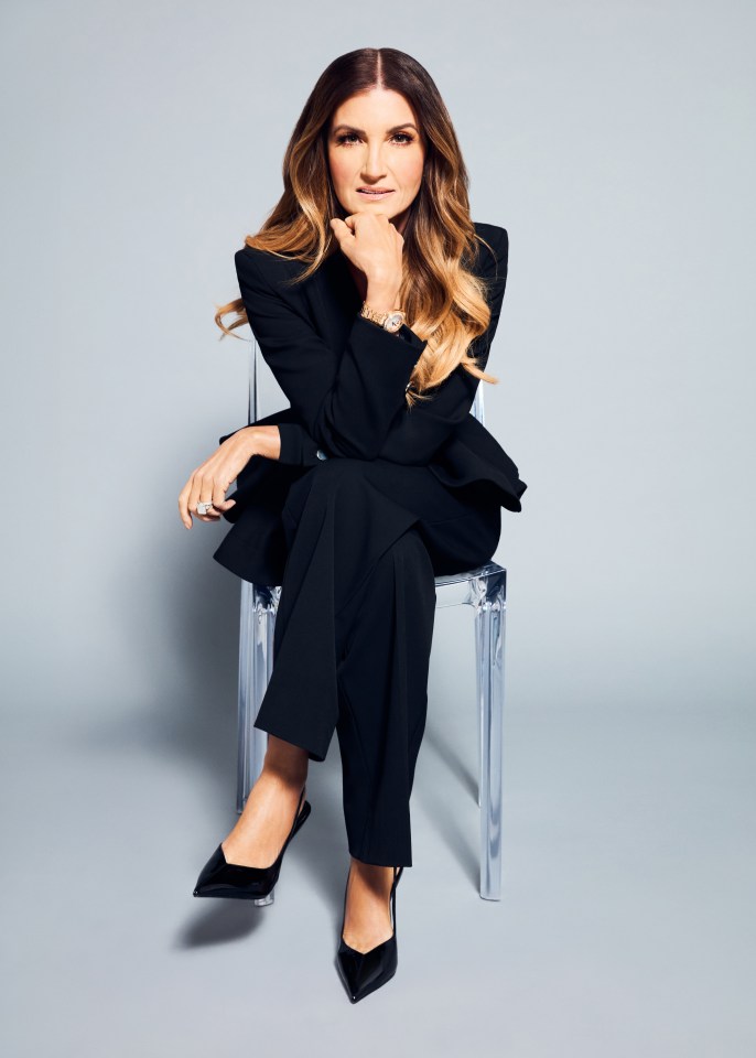 Karren Brady seated on a clear chair.