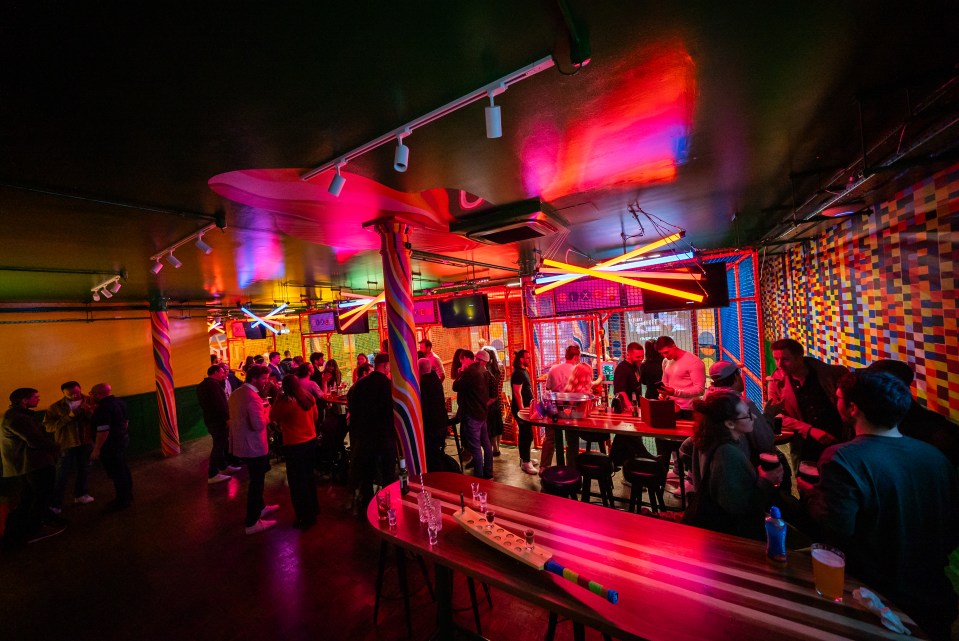 Crowded bar with neon lighting and games.