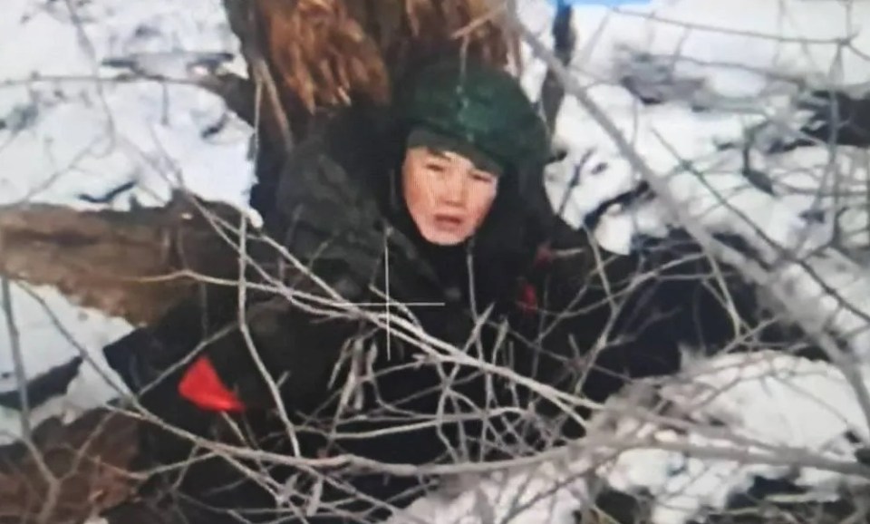 North Korean soldier taking cover behind trees in snowy conditions.