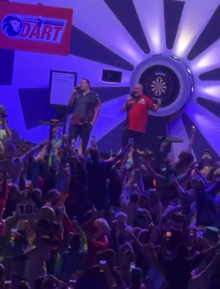 Stephen Bunting and Adrian Lewis singing at a darts exhibition.