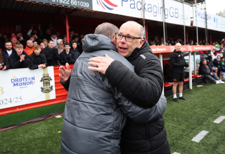 Two soccer managers embracing on a field.