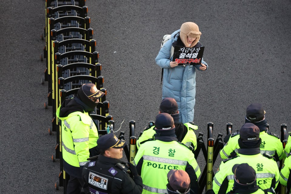 An anti-Yoon protester holding signs that read, “Arrest Yoon Suk Yeol immediately"