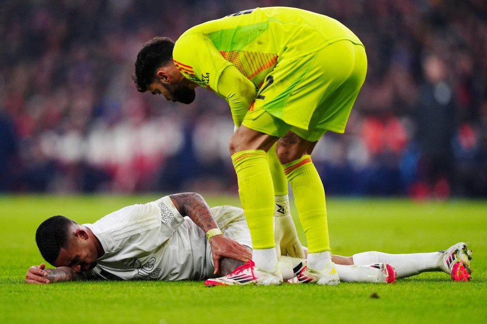 Arsenal goalkeeper attending to an injured player on the field.