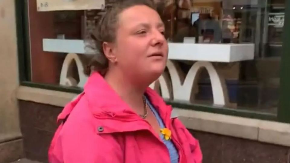 Woman in pink jacket speaking outside a McDonald's.