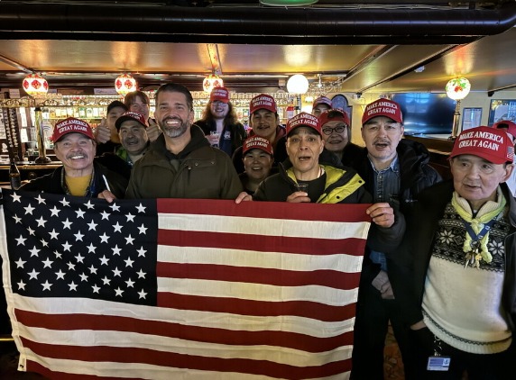 Donald Trump Jr. with a group of people in Greenland holding an American flag.