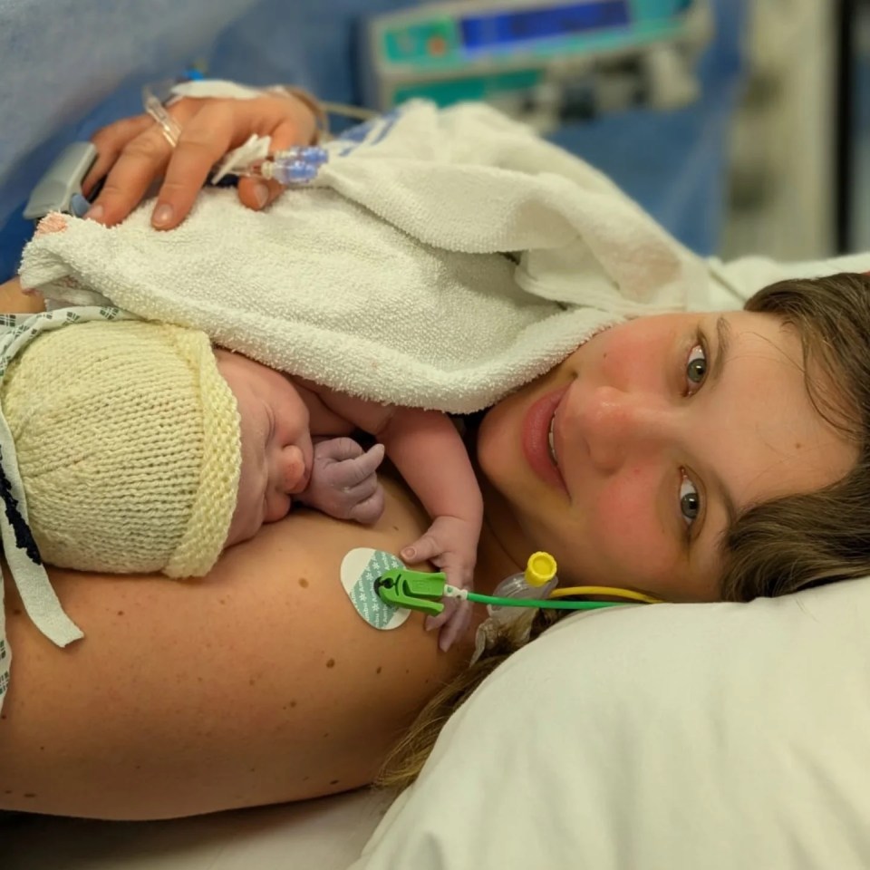 A mother holding her newborn baby in a hospital bed.