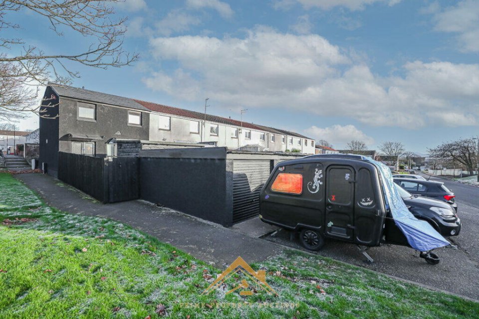 Exterior view of a black house and a black caravan.