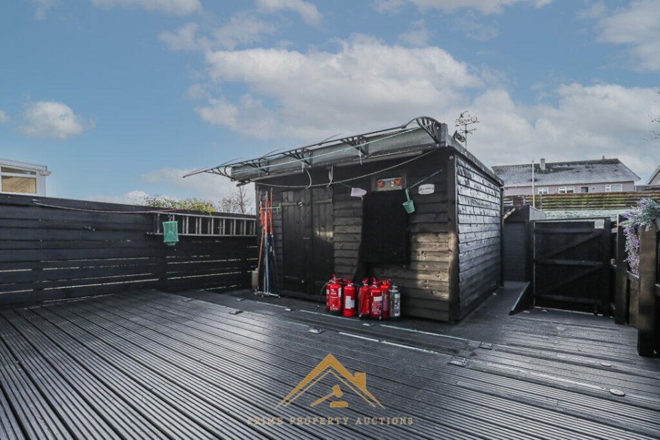 Black shed and deck in a backyard.