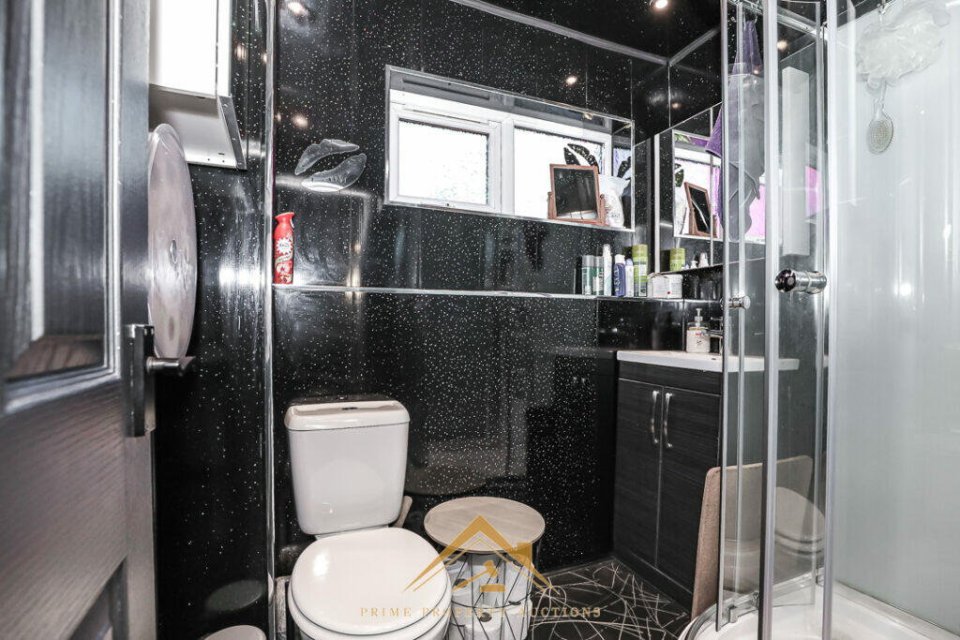 Black bathroom with toilet, shower, and dark-colored vanity.