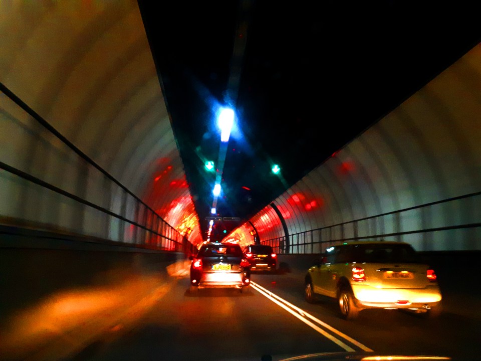 Cars driving through the Blackwall Tunnel in London at night.