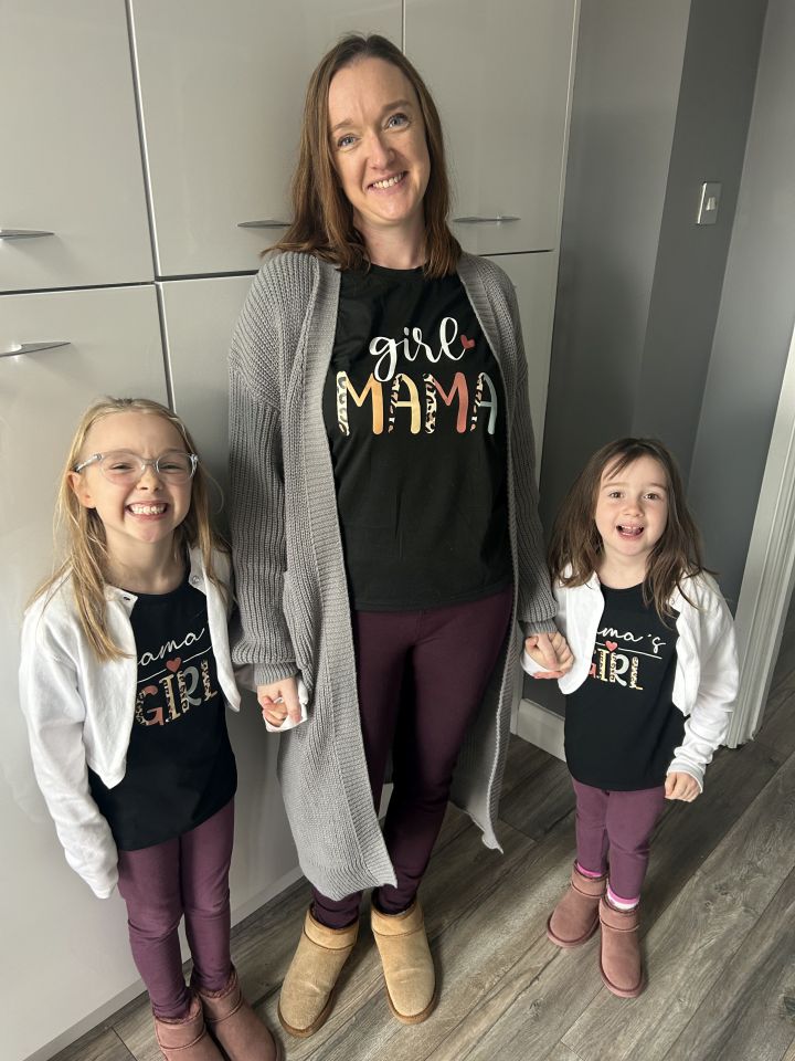 A mother and her two daughters wearing matching "Mama's Girl" t-shirts.