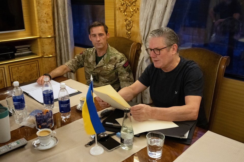 Keir Starmer, British Prime Minister, reviews documents while being briefed by a military assistant on a train to Kyiv.