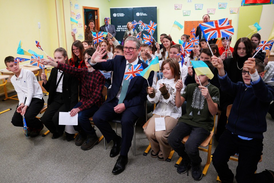 Keir Starmer with Ukrainian schoolchildren waving British and Ukrainian flags.