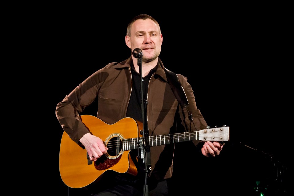 David Gray performing live with an acoustic guitar.