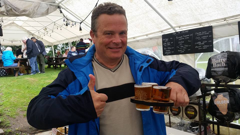 Man giving thumbs up while holding a beer flight.