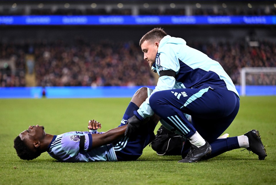 Bukayo Saka of Arsenal receiving medical attention on the field.