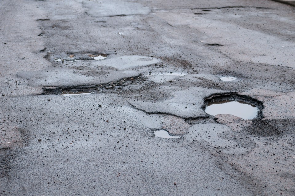 Car driving past a pothole in the road.