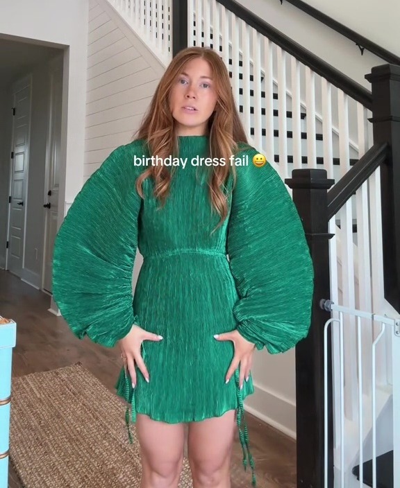 Woman in green pleated dress, disappointed with her birthday outfit.