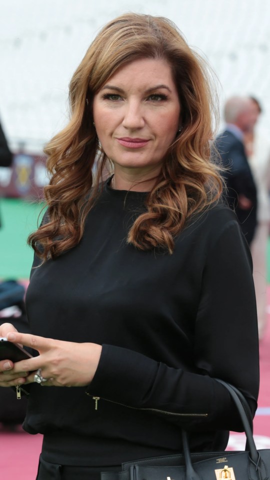 Karen Brady looking at her phone at a West Ham United soccer match.