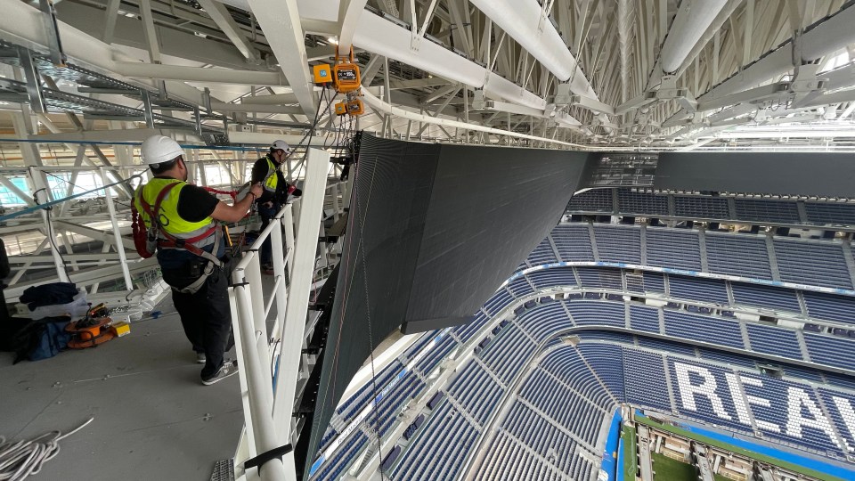 Workers installing a large scoreboard screen at the Santiago Bernabéu Stadium.