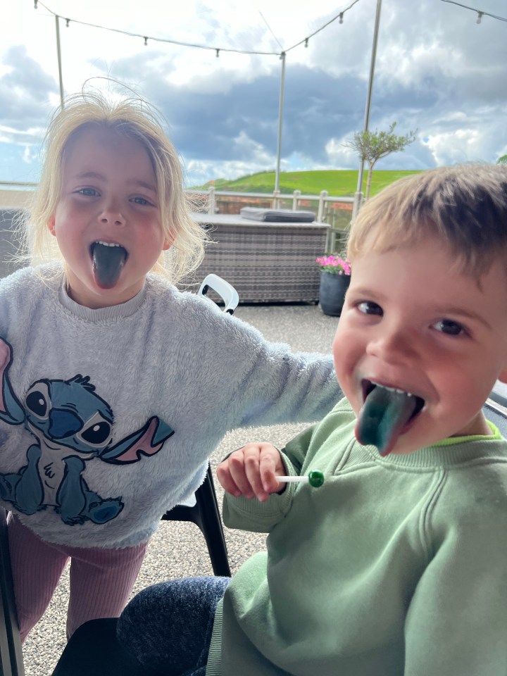 Two young children with blue-colored tongues from a lollipop.