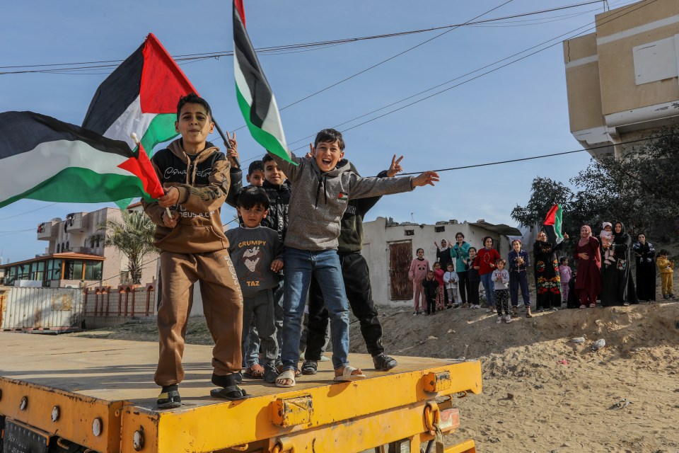 Palestinian children waving flags on a truck following a ceasefire.