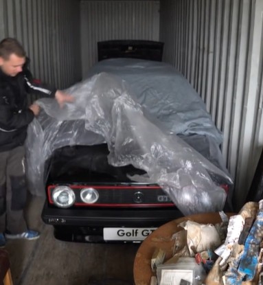 A man uncovers a classic Golf GTI car in a shipping container.