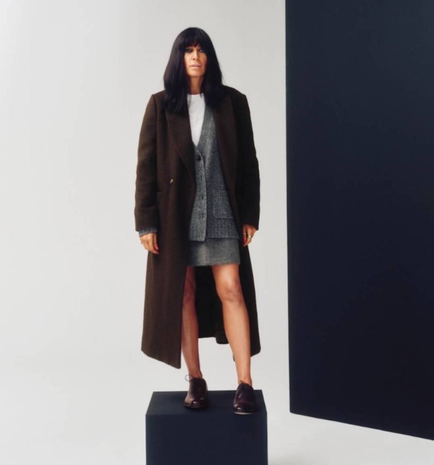 Claudia Winkleman wearing a brown coat, grey cardigan, and skirt.