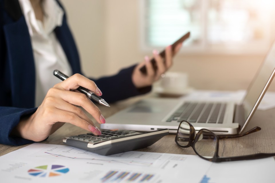 Close-up of a businesswoman using a calculator and laptop.