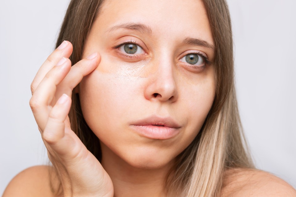 Woman applying concealer under her eyes.