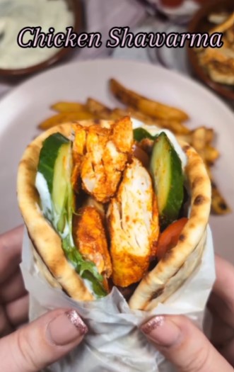 Chicken shawarma in a pita bread with cucumber and fries.