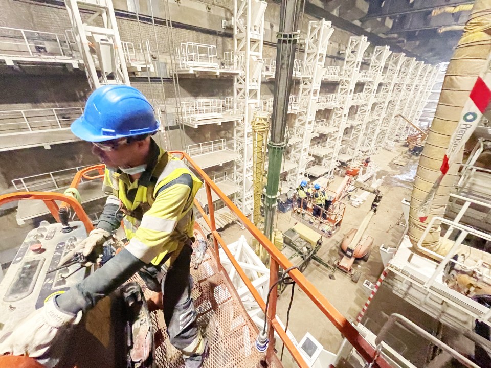 Construction worker operating a lift to place metal structures in a stadium hypogeum.