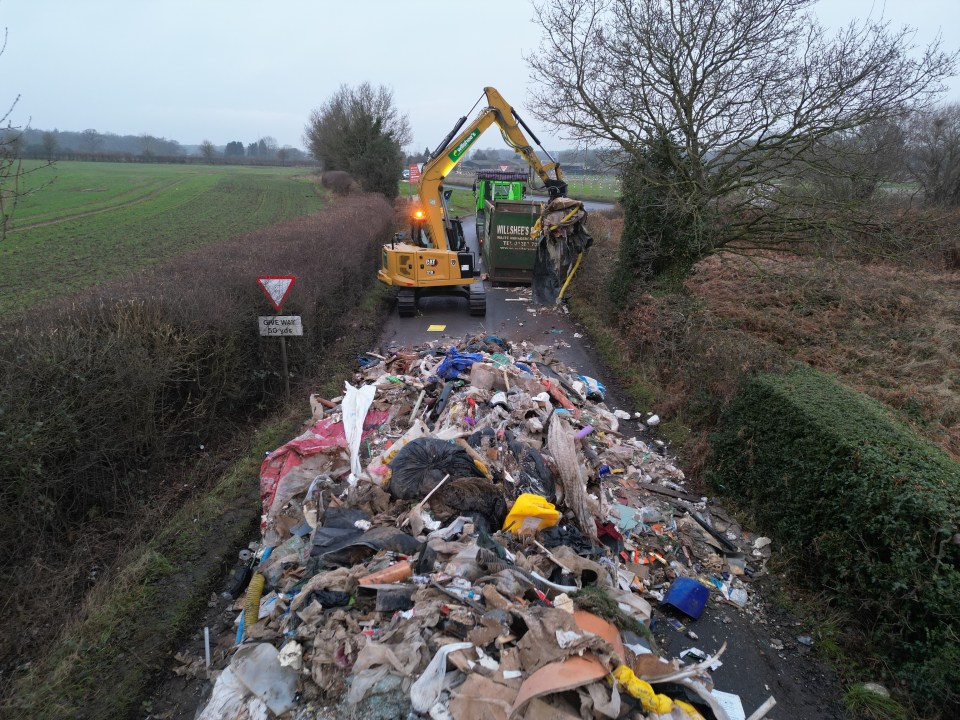 Contractors removing a large pile of fly-tipped waste.