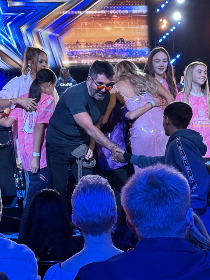 Simon Cowell shaking hands with Coronation Street teen star Kyran Bowes and other young people.