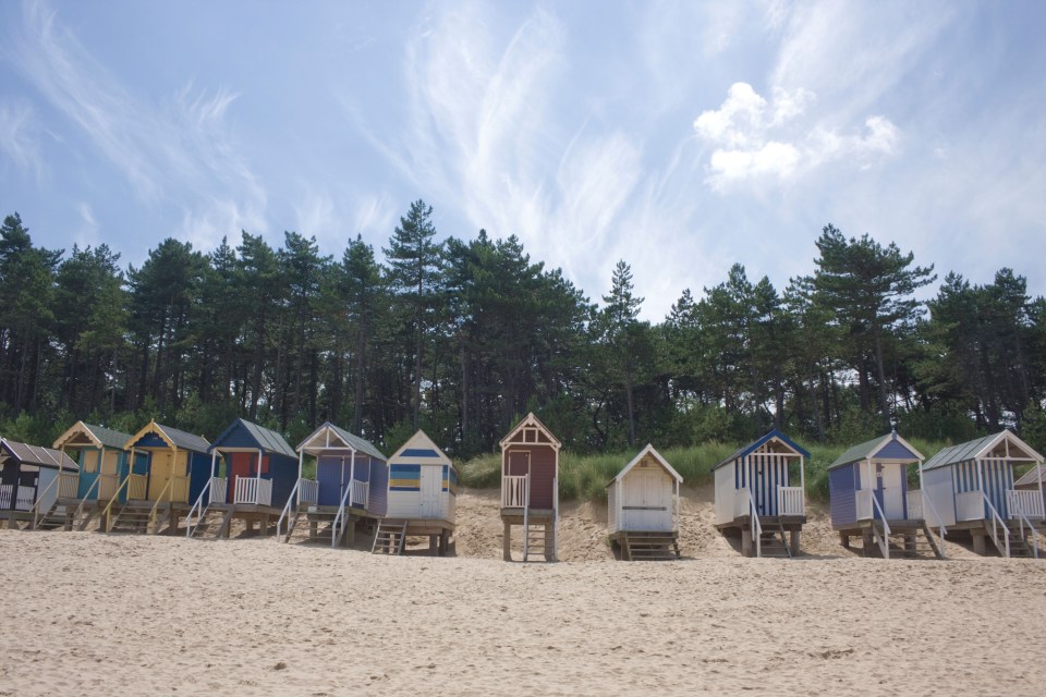 Row of colorful beach huts on a sandy beach.