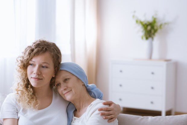 A woman with cancer smiles while hugging her daughter.