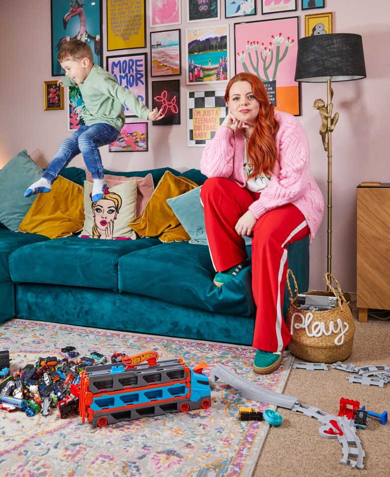 A mother and son in their living room.  The son is jumping on a sofa.