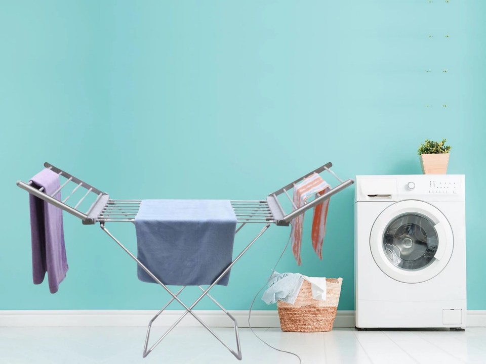 Heated clothes airer with laundry next to a washing machine.