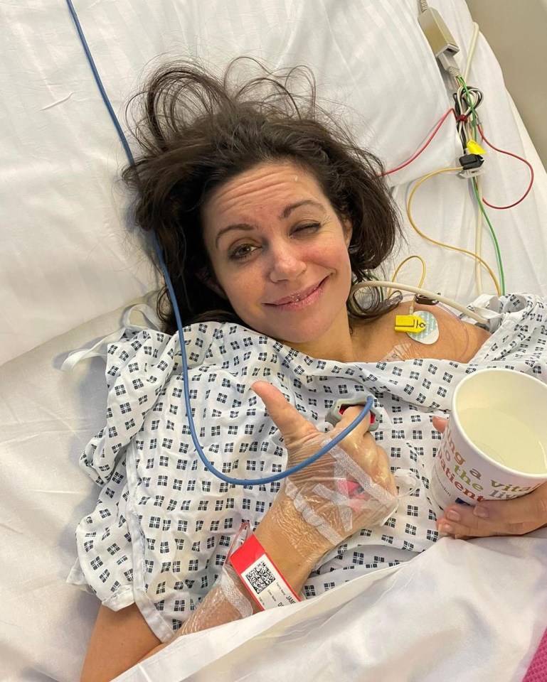 Woman in hospital bed giving thumbs up.