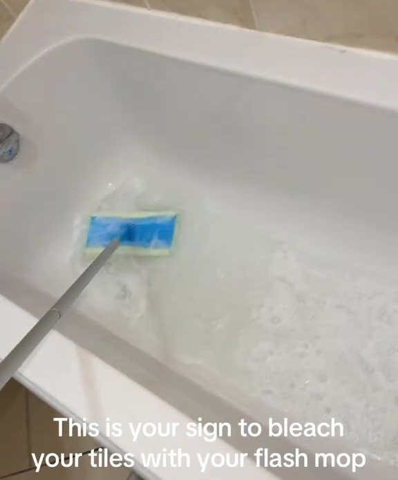 Cleaning a bathtub with a brush, revealing significant dirt in the soapy water.