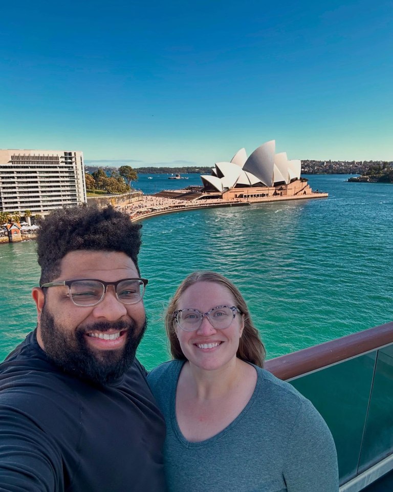 Couple on cruise ship with Sydney Opera House in background.