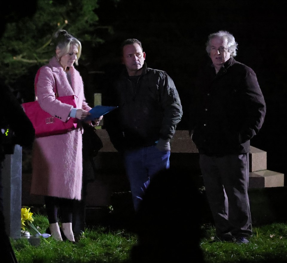 Three people at night looking at a grave with a note.