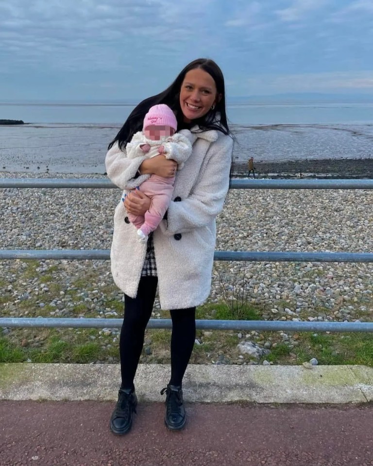 Woman holding a baby near the water.