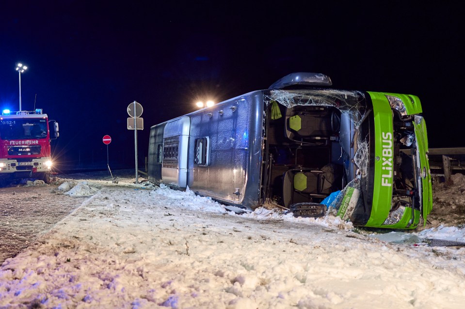 A FlixBus on its side in the snow, with emergency vehicles present.